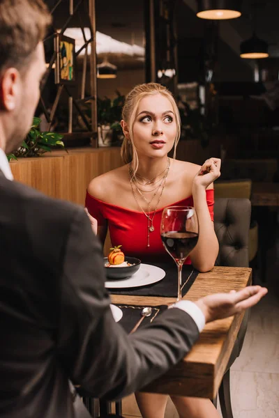 Dreamy girl sitting near sweet dessert with boyfriend in restaurant — Stock Photo