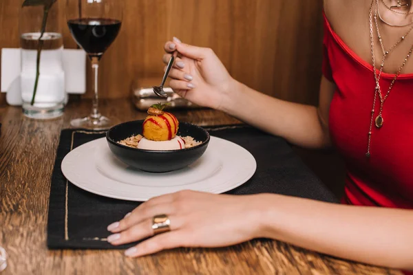 Женская рука держит ложку возле сладкого десерта в миске — стоковое фото