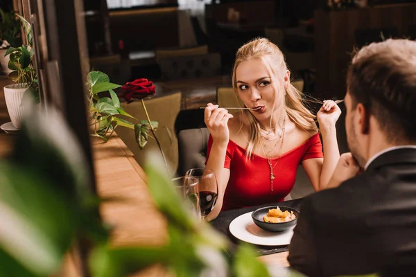 Novia comiendo postre dulce mientras mira al hombre en el restaurante - foto de stock