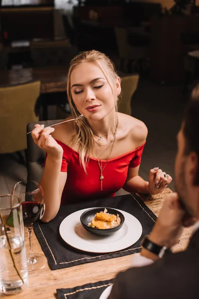 Girlfriend eating sweet dessert while sitting near boyfriend in restaurant — Stock Photo