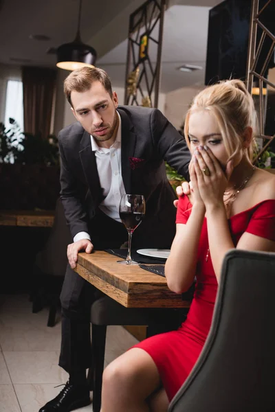Selective focus of blonde woman crying near worried boyfriend in restaurant — Stock Photo
