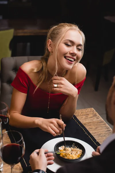 Happy woman laughing  near boyfriend while sharing dessert in restaurant — Stock Photo