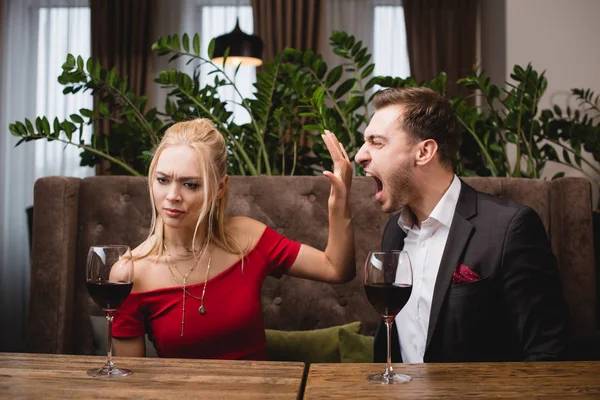 Offended woman gesturing to stop screaming boyfriend in restaurant — Stock Photo