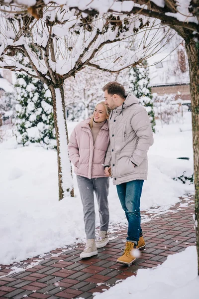 Щасливий чоловік і жінка обіймаються і ходять в зимовому парку — стокове фото