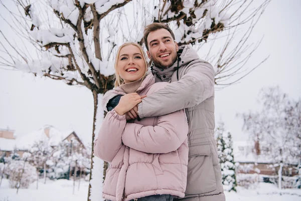 Feliz hombre y mujer se abrazan en el día en invierno - foto de stock