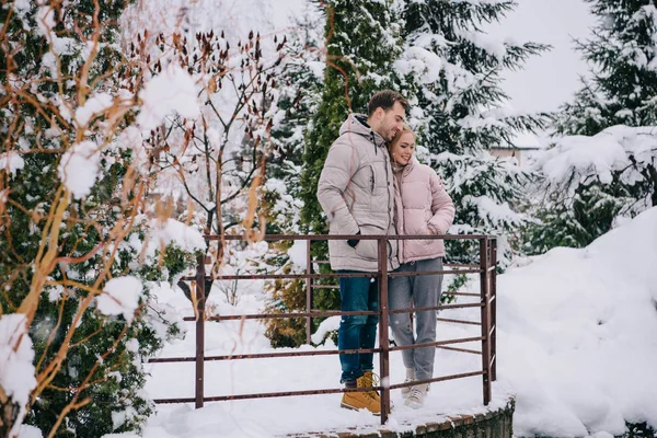 Романтическая пара, стоящая и обнимающаяся в зимнем парке — стоковое фото