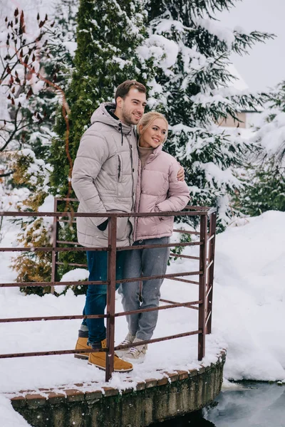 Feliz pareja de pie y abrazándose en el frío parque de invierno - foto de stock