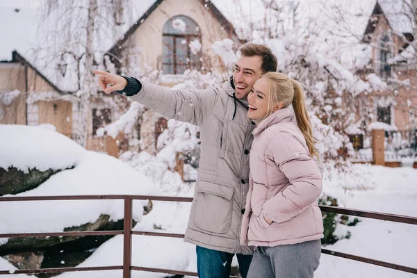 Hombre guapo de pie con novia rubia y señalando con el dedo - foto de stock