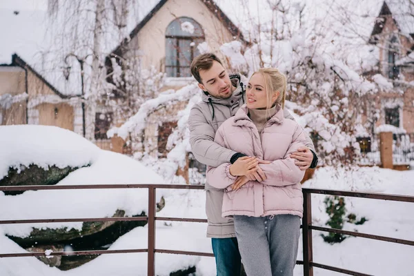 Schöner Mann schaut fröhliche Freundin an und umarmt sie im Winter — Stockfoto