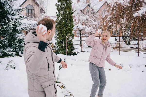 Alegre pareja jugando con bolas de nieve en invierno - foto de stock