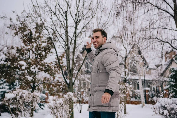 Hombre alegre lanzando bola de nieve en invierno - foto de stock