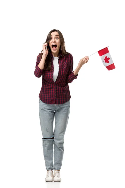Mujer emocionada sosteniendo bandera canadiense y hablando en el teléfono inteligente aislado en blanco - foto de stock