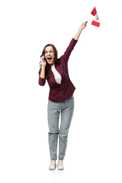 Mujer excitada en ropa casual sosteniendo bandera canadiense y hablando en un teléfono inteligente aislado en blanco - foto de stock