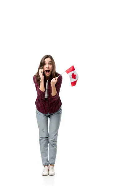 Femme surprise tenant drapeau canadien et parlant sur smartphone isolé sur blanc — Photo de stock