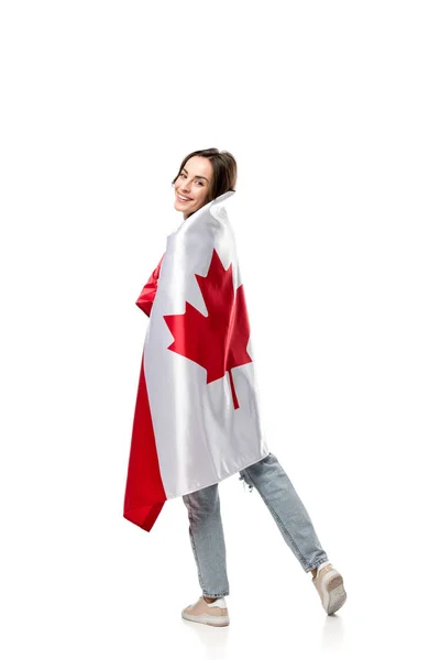 Bela mulher sorridente coberto de bandeira canadense olhando para a câmera isolada no branco — Fotografia de Stock
