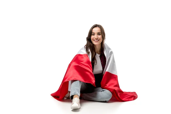 Sonriente mujer cubierta de bandera canadiense mirando a la cámara aislada en blanco - foto de stock