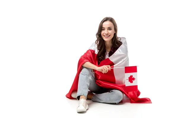 Atractiva mujer cubierta de bandera canadiense sosteniendo bandera de hoja de arce aislada en blanco - foto de stock