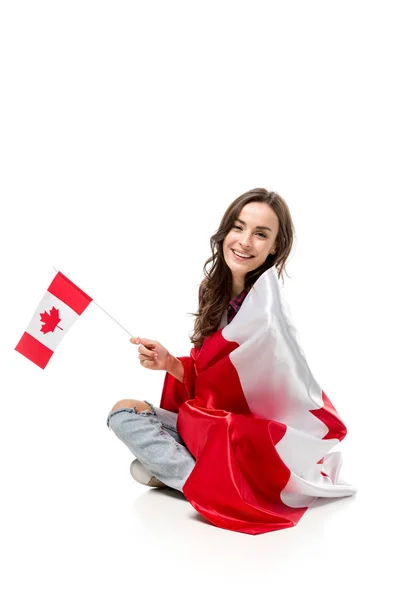 Beautiful smiling woman covered in canadian flag holding maple leaf flag isolated on white — Stock Photo
