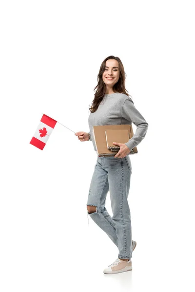 Beautiful smiling female student holding canadian flag and notebooks isolated on white — Stock Photo