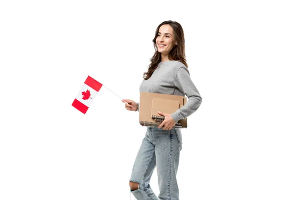 Estudiante sonriente sosteniendo bandera canadiense y cuadernos aislados en blanco - foto de stock
