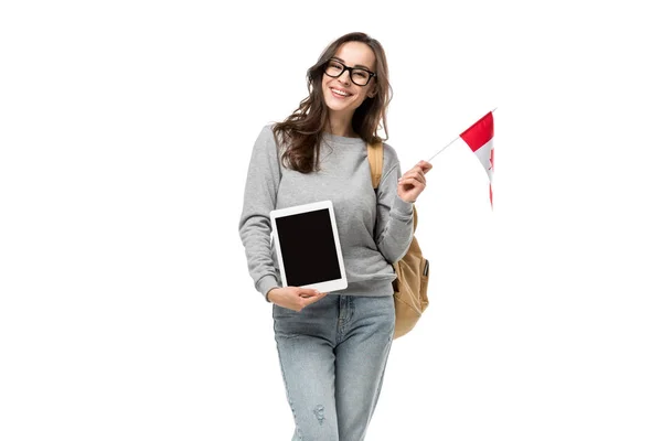 Estudiante sonriente sosteniendo bandera canadiense y presentando tableta digital con pantalla en blanco aislada en blanco - foto de stock