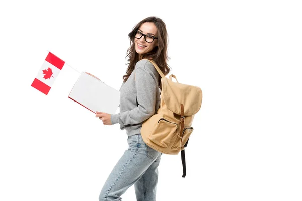 Étudiante heureuse avec sac à dos tenant drapeau canadien et cahier isolé sur blanc — Photo de stock