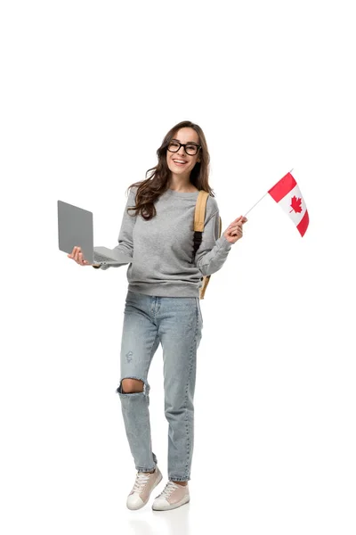 Щаслива студентка в окулярах тримає ноутбук і канадський прапор ізольовано на білому — стокове фото