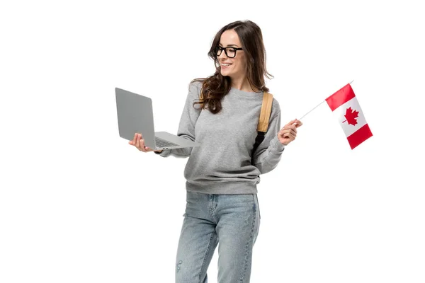 Sorridente estudante do sexo feminino em óculos segurando laptop e bandeira canadense isolado no branco — Fotografia de Stock