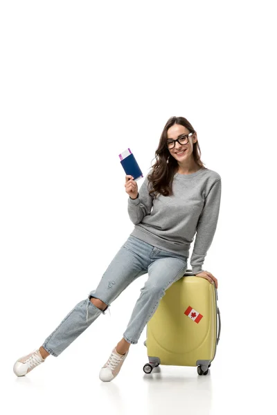 Mulher feliz sentado em mala com passaporte e passagens aéreas isoladas em branco, conceito de viagem — Fotografia de Stock