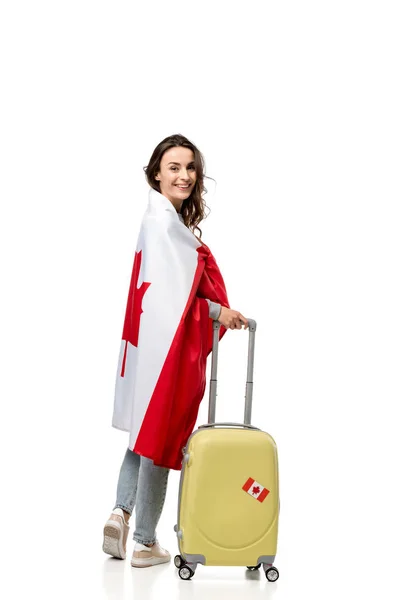 Smiling woman covered in canadian flag with suitcase isolated on white, travel concept — Stock Photo