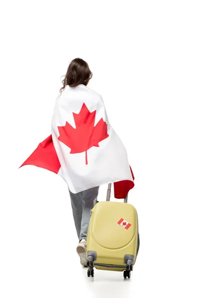 Вид ззаду жінки, вкрита канадським прапором з валізою ізольовано на білому, концепція подорожей — стокове фото