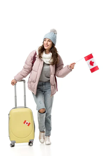 Студентка в зимовому одязі з валізою тримає канадський прапор ізольовано на білому — стокове фото