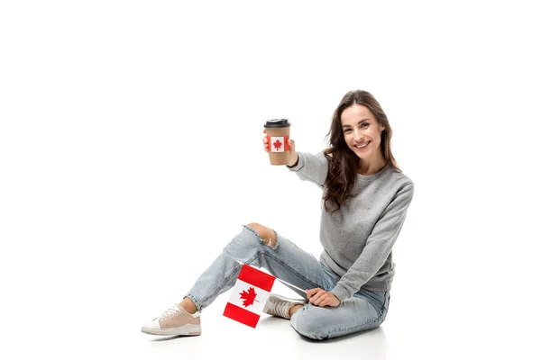 Femme heureuse avec drapeau canadien tenant tasse à café avec autocollant feuille d'érable isolé sur blanc — Photo de stock
