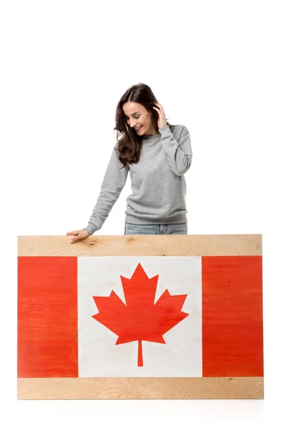 Sorrindo mulher de pé perto de tábua de madeira com bandeira canadense e olhando para longe isolado no branco — Fotografia de Stock