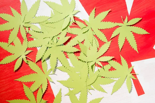 Hojas de cannabis de papel sobre bandera canadiense, concepto de legalización de la marihuana - foto de stock