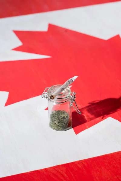 Selective focus of cannabis in glass jar with joint on canadian flag, marijuana legalization concept — Stock Photo