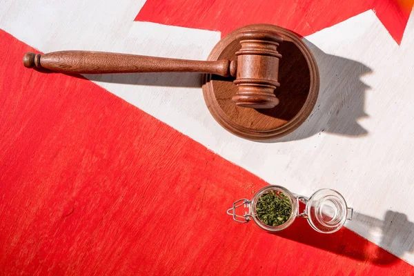 Cannabis in glass jar with wooden gavel on canadian flag, marijuana legalization concept — Stock Photo