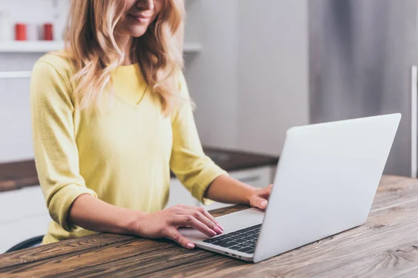 Vista ritagliata di donna sorridente digitando sul computer portatile a casa — Foto stock