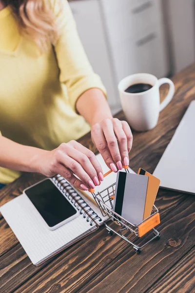 Vista ritagliata della donna che tiene il carrello della spesa con carte di credito — Foto stock