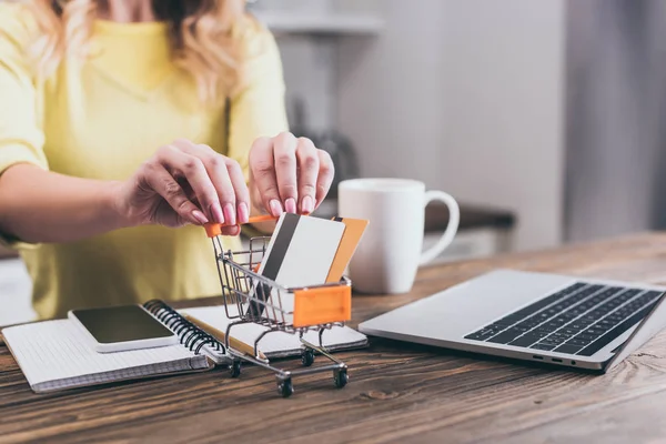 Mise au point sélective des cartes de crédit dans le chariot d'achat de jouets avec femme sur fond — Photo de stock