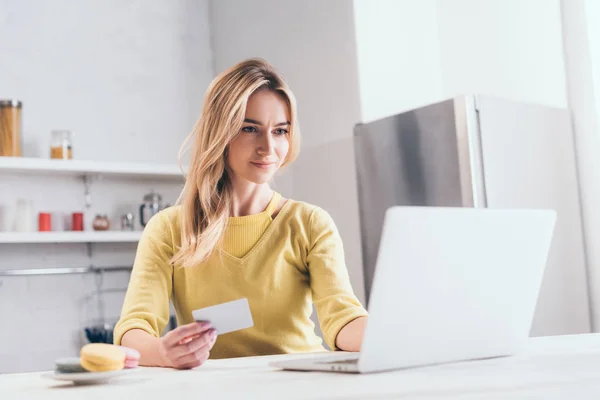 Mujer atractiva celebración de la tarjeta de crédito mientras se utiliza el ordenador portátil - foto de stock