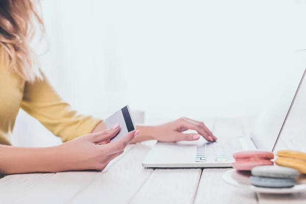 Vista recortada de la mujer usando el ordenador portátil mientras sostiene la tarjeta de crédito - foto de stock