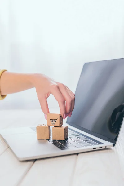 Cropped view of woman putting toy paper box on laptop keyboard — Stock Photo