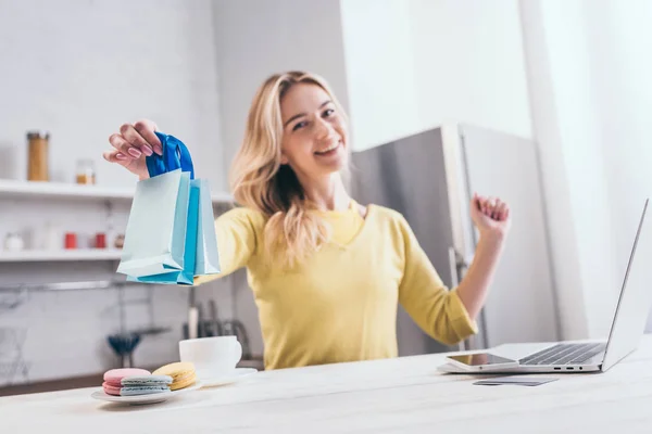 Selective focus of toy shopping bags in hand of smiling woman — Stock Photo