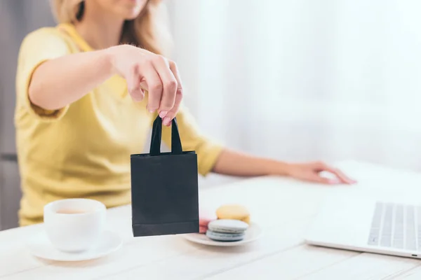 Selective focus of woman holding small black shopping bag at home — Stock Photo
