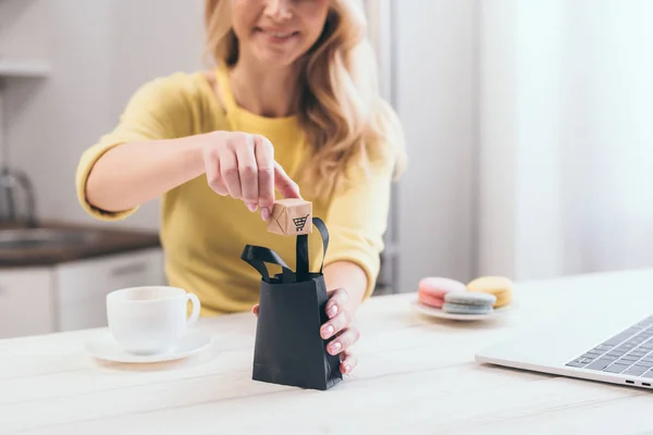 Selektiver Fokus der Frau, die Spielzeugpapierschachtel in kleine schwarze Einkaufstasche steckt — Stockfoto