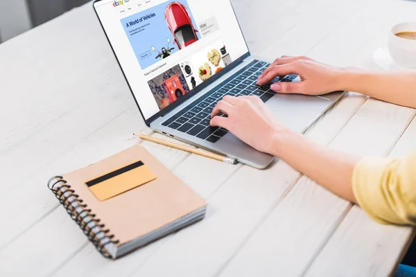 Vista recortada de la mujer usando el ordenador portátil con el sitio web de eBay en la pantalla - foto de stock