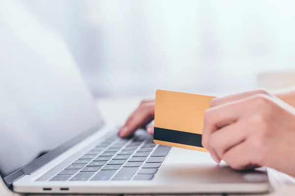 Foco seletivo do cartão de crédito na mão da mulher usando laptop — Fotografia de Stock