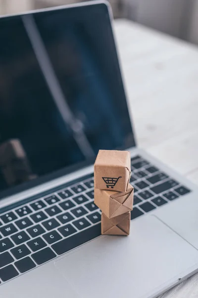 Enfoque selectivo de cajas de papel de juguete con símbolo de compra en el teclado del ordenador portátil - foto de stock