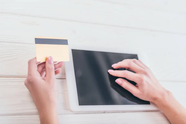 Recortado ciew de mujer celebración de tarjeta de crédito cerca de tableta digital con pantalla en blanco - foto de stock